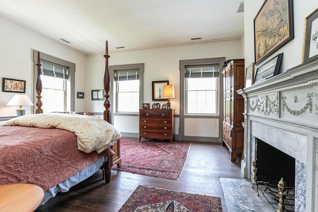 bedroom with a high end fireplace, crown molding, and dark wood-type flooring