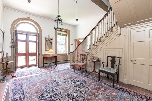 foyer featuring french doors, ornamental molding, and a healthy amount of sunlight