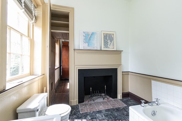 bathroom with a relaxing tiled tub and toilet