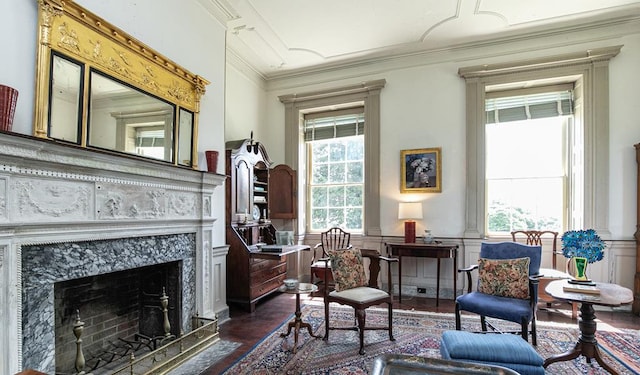 sitting room with a high end fireplace, dark wood-type flooring, and crown molding