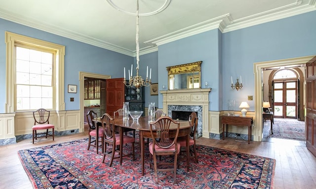 dining space featuring a fireplace, light hardwood / wood-style floors, plenty of natural light, and crown molding