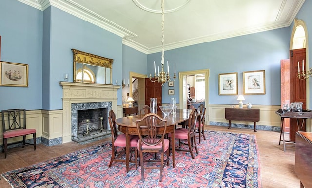 dining area featuring light hardwood / wood-style floors, an inviting chandelier, ornamental molding, and a premium fireplace