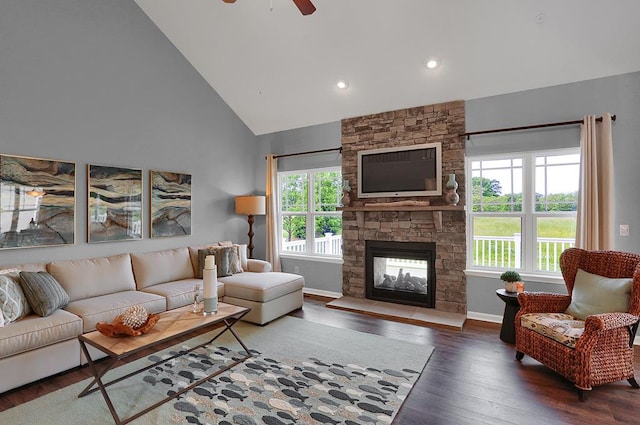 living room with a stone fireplace, ceiling fan, high vaulted ceiling, and dark wood-type flooring