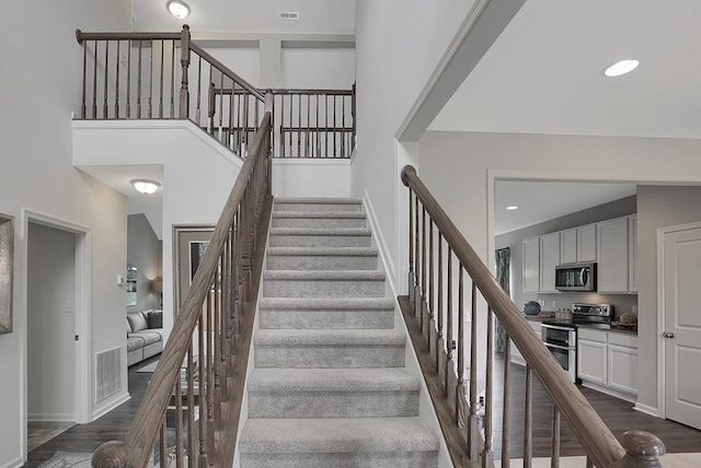 staircase featuring a high ceiling and hardwood / wood-style flooring