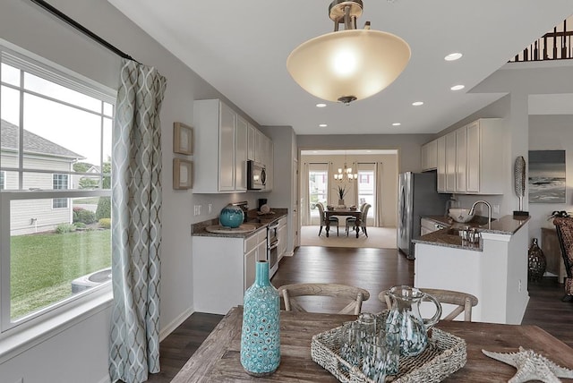 kitchen featuring appliances with stainless steel finishes, dark stone counters, dark wood-type flooring, sink, and white cabinets