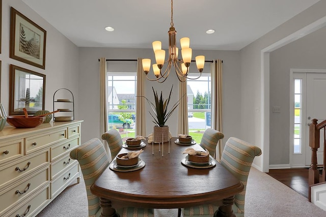 dining area with a wealth of natural light, hardwood / wood-style floors, and a notable chandelier