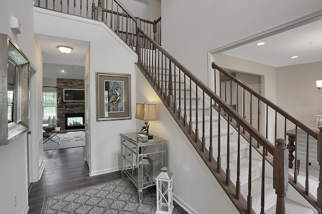 stairway with a fireplace and hardwood / wood-style flooring