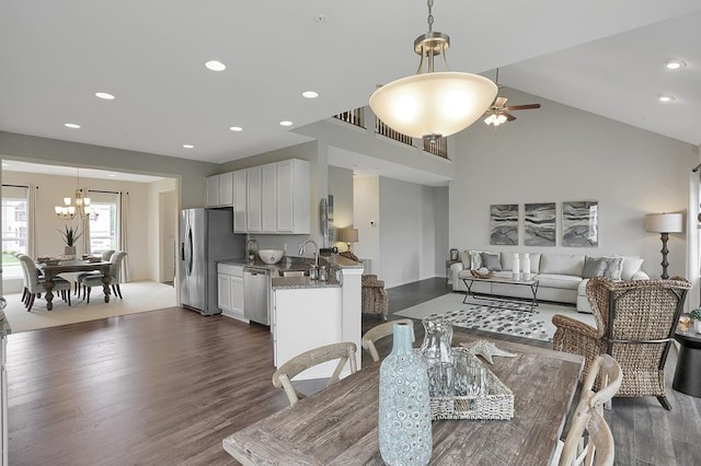 dining room featuring ceiling fan, vaulted ceiling, sink, and dark wood-type flooring