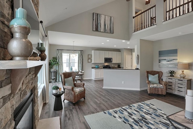 living room featuring a towering ceiling, dark hardwood / wood-style floors, and a stone fireplace