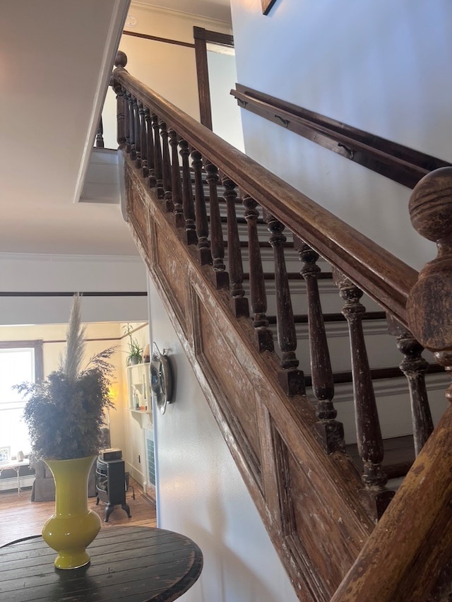 stairs featuring crown molding and wood finished floors