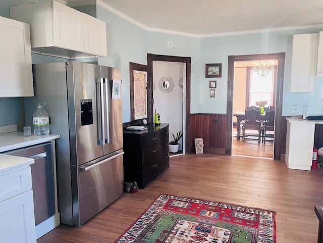 kitchen with wood finished floors, light countertops, appliances with stainless steel finishes, white cabinetry, and crown molding