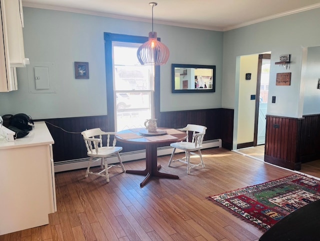 dining space with breakfast area, a healthy amount of sunlight, wood finished floors, and ornamental molding