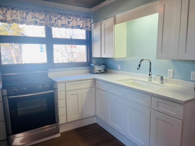 kitchen featuring a sink, range with electric cooktop, ornamental molding, and white cabinetry