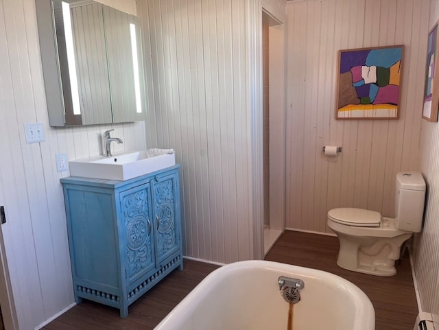 bathroom with baseboard heating, toilet, vanity, and a freestanding tub