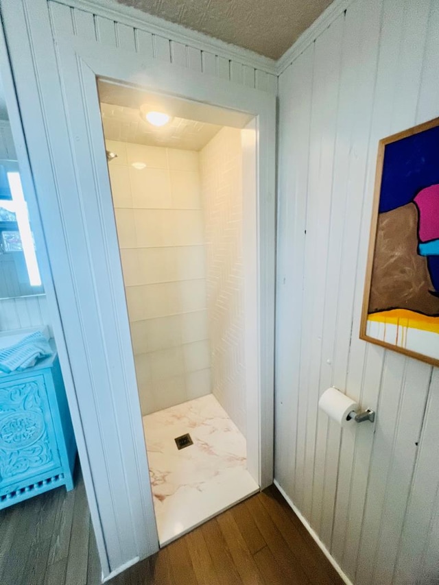 bathroom featuring wood finished floors, a shower stall, and wood walls