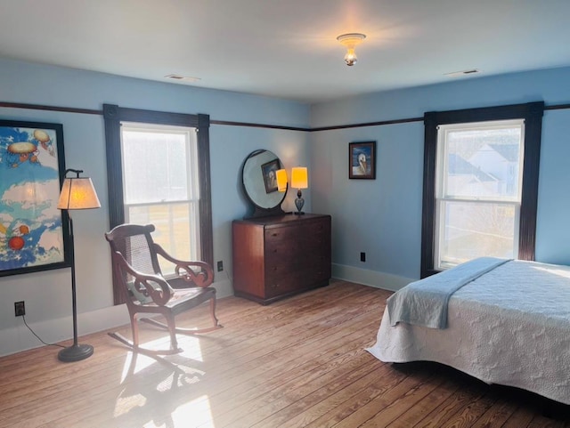 bedroom with visible vents, baseboards, and hardwood / wood-style flooring