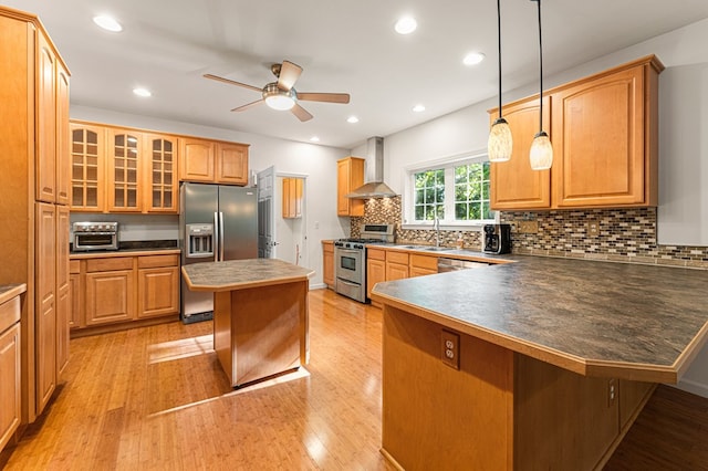 9333 Red Bank Rd, Nassawadox, VA 23413 - kitchen featuring appliances with stainless steel finishes, wall chimney exhaust hood, a ceiling fan, light wood-style flooring, and a peninsula