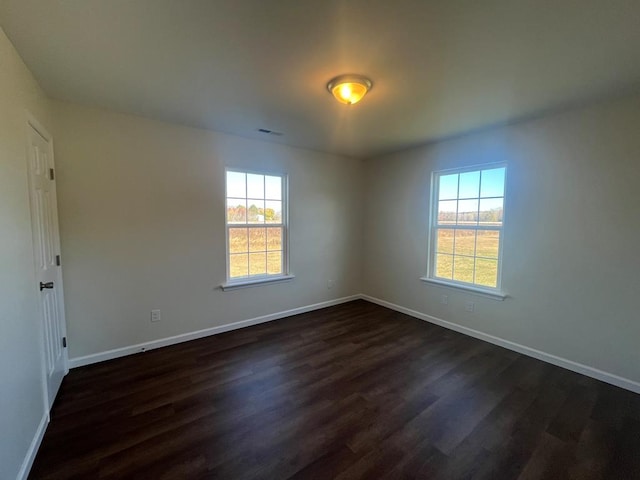 spare room featuring a wealth of natural light and dark hardwood / wood-style flooring