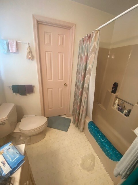 bathroom featuring shower / tub combo and toilet