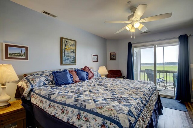 bedroom with a water view, dark wood-type flooring, access to exterior, and ceiling fan