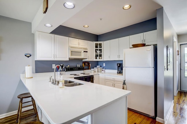 kitchen with white cabinetry, white appliances, and kitchen peninsula