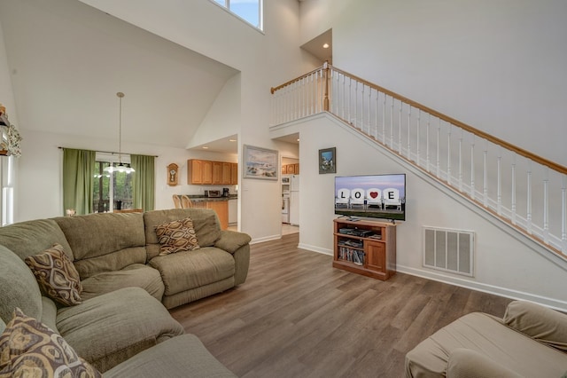 living area featuring high vaulted ceiling, stairs, wood finished floors, and visible vents