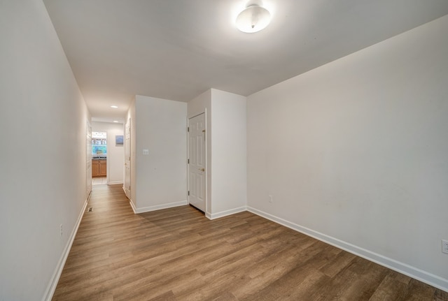 spare room with baseboards, recessed lighting, and wood finished floors