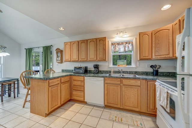 kitchen with dark countertops, a sink, white appliances, a peninsula, and light tile patterned floors