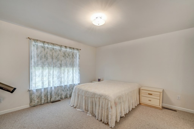bedroom featuring baseboards, light carpet, and visible vents