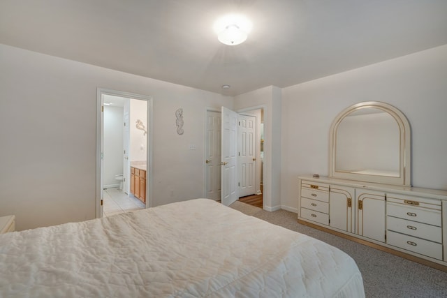 bedroom with baseboards, ensuite bathroom, and light colored carpet