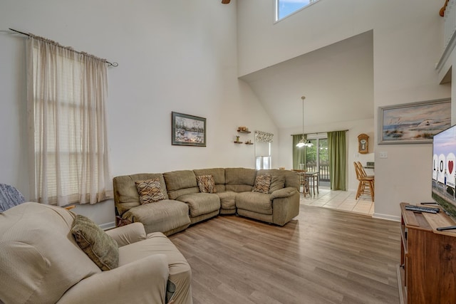 living room featuring an inviting chandelier, light wood finished floors, and a towering ceiling