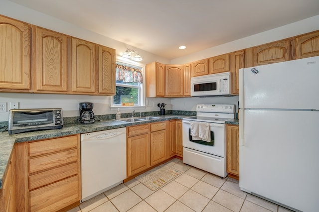 kitchen featuring dark countertops, a sink, light tile patterned floors, a toaster, and white appliances