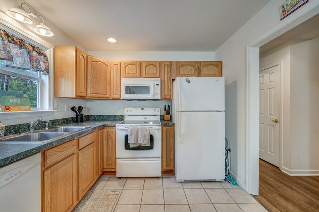 kitchen featuring dark countertops, a sink, light tile patterned floors, recessed lighting, and white appliances