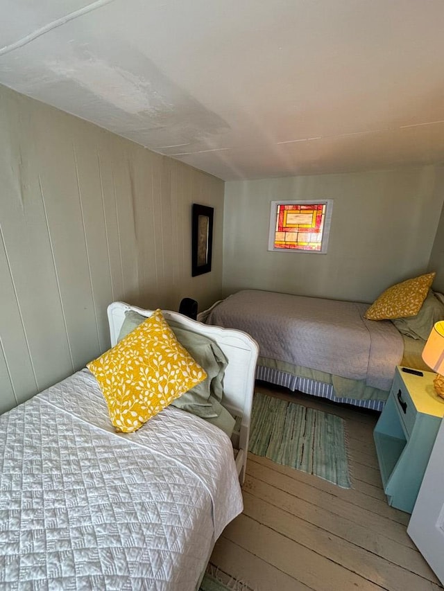 bedroom with wooden walls and hardwood / wood-style flooring