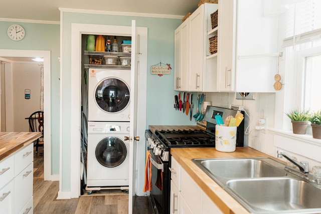 laundry area with crown molding, sink, stacked washer and dryer, and light hardwood / wood-style floors