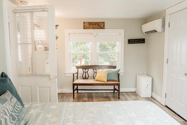 bedroom with a wall mounted air conditioner and hardwood / wood-style flooring