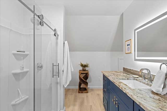 full bath with baseboards, lofted ceiling, a stall shower, wood finished floors, and vanity