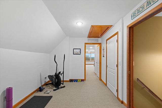 workout area featuring visible vents, carpet flooring, baseboards, attic access, and vaulted ceiling