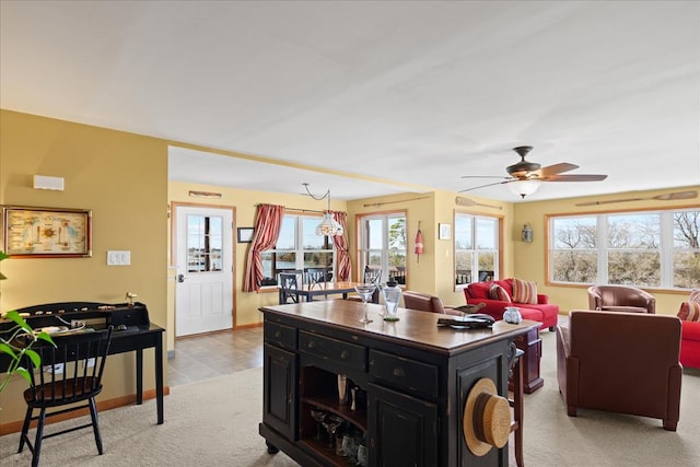 kitchen with baseboards, light carpet, dark cabinetry, and a ceiling fan