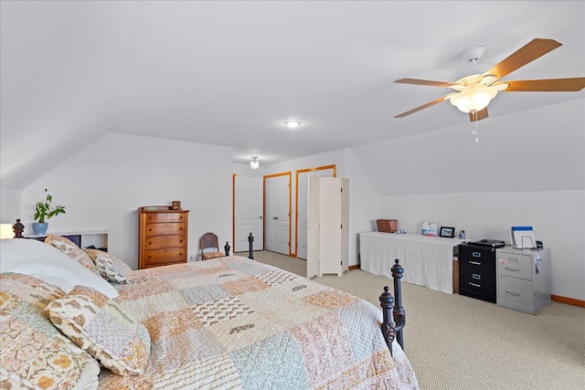 bedroom featuring light colored carpet, two closets, and vaulted ceiling