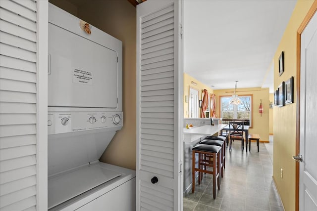 clothes washing area featuring stacked washer / dryer and laundry area