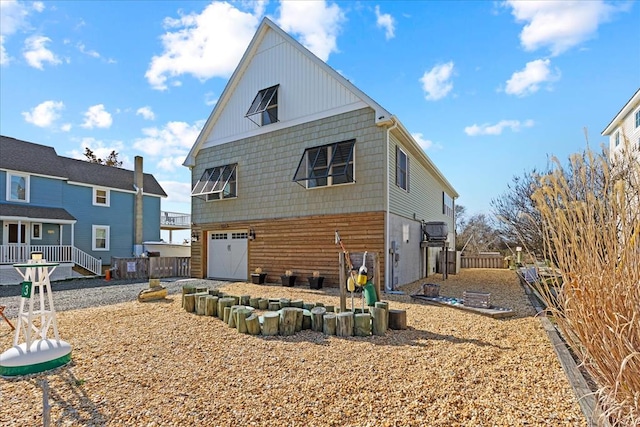 back of house with fence, a garage, and driveway