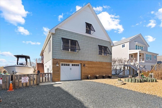 exterior space featuring gravel driveway, an attached garage, and fence