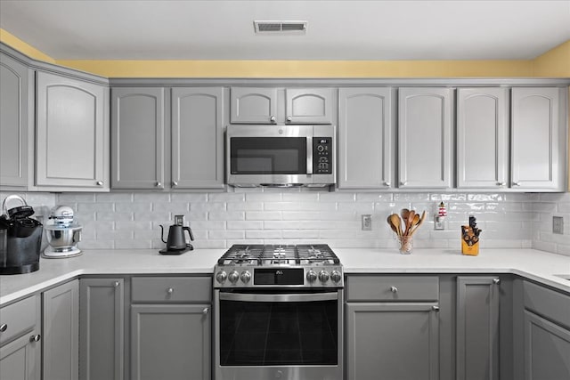 kitchen featuring tasteful backsplash, visible vents, appliances with stainless steel finishes, and gray cabinetry