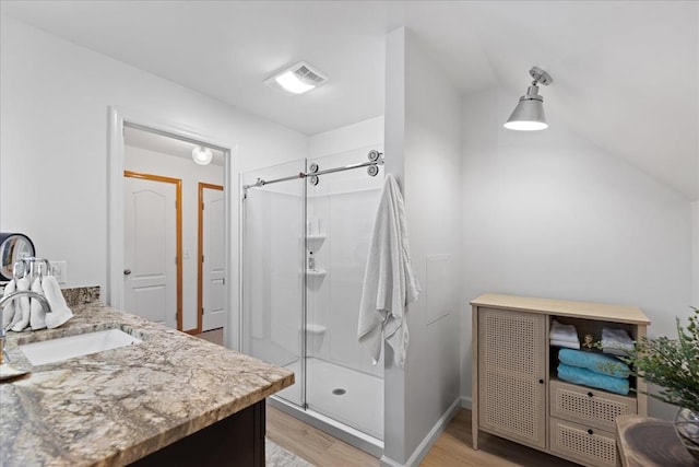 full bath with vanity, a shower stall, wood finished floors, and visible vents