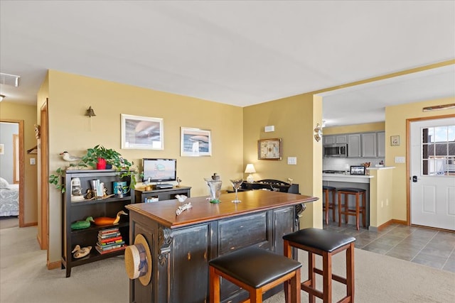 bar featuring stainless steel microwave, light tile patterned flooring, decorative backsplash, baseboards, and light colored carpet