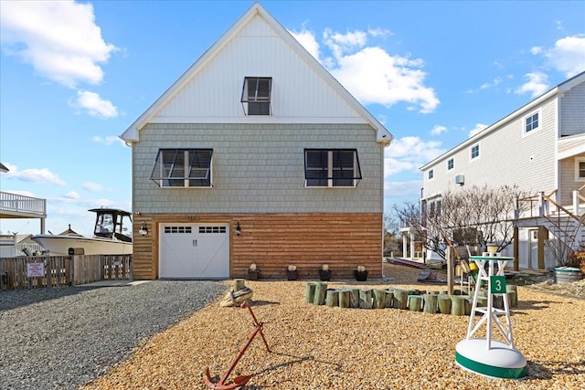 view of home's exterior with gravel driveway, an attached garage, and fence