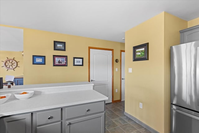 kitchen with gray cabinetry, light countertops, and freestanding refrigerator