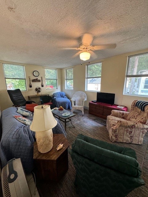 living room with a wealth of natural light, ceiling fan, carpet, and a textured ceiling