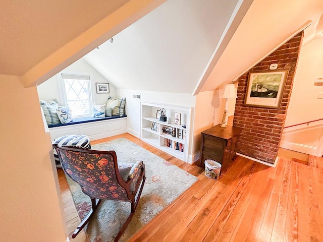 interior space with hardwood / wood-style floors, baseboards, vaulted ceiling, and built in shelves
